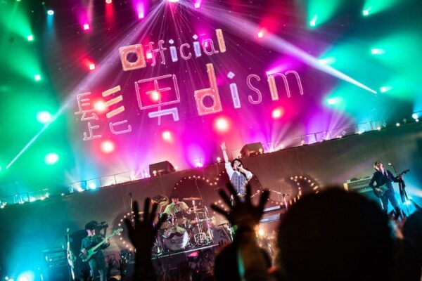 ヒット曲を連発し続けているバンド「Official髭男dism(ヒゲダン)」。 数々のタイアップとポップな楽曲センスで多くのファンのいる大人気アーティストです。 そんなヒゲダンのバンド名の由来やメンバーの結成秘話などのエピソードについて紹介します！ ＃ヒゲダン(Official髭男dism)とは？ まず、Official髭男dismは、「オフィシャルヒゲダンディズム」と読みます。 略して「ヒゲダン」です。 表記も読み方もかなり独特ですよね。 メンバーは、 ボーカル&ピアノ : 藤原聡 (ふじはら さとし) ギター : 小笹大輔 (おざさ だいすけ) ベース&サックス : 楢崎誠 (ならさき まこと) ドラム : 松浦匡希 (まつうら まさき) の4人です。 2012年に結成され、2015年にインディーズデビュー。 2018年に「ノーダウト」でメジャーデビューしました。 メジャーデビューにして、いきなりフジテレビの月9ドラマ「コンフィデンスマンJP」の主題歌に抜擢され、大注目されました。 「ノーダウト」から引き続いて映画版「コンフィデンスマンJP」の主題歌になった2ndシングル「Pretender」はBillboard Japan Hot 100で1位を獲得しました。 そして、2019年末には「第70回NHK紅白歌合戦」に初出場しました。 ポップな楽曲とピアノロックなサウンド、伸びやかなハイトーンボーカルが特徴的で、耳に残る印象的なヒット曲を連発しています。 ＃ヒゲダン(Official髭男dism)のバンド名の由来 では「Official髭男dism」という独特なバンド名の由来はどこにあるのでしょうか？ オフィシャルホームページのプロフィールには、 「髭の似合う歳になっても、誰もがワクワクす るような音楽をこのメンバーでずっと続けて行きたいという意思が込められている。 」 と書かれています。 そう聞くと、すごく前向きでカッコ良いバンド名に見えてきますね。 でも、実際のところは、最初はふざけて付けた名前だったようです。 きっかけは、ベース&サックスの楢崎誠が、誰だかわからない髭もじゃギタリストのポスターを見て思いついたそうです。 ふざけて付けたにしても、凄いネーミングセンスですよね。 長いバンド名なのに、一度聞いたら忘れないインパクトがあります。 ＃ヒゲダン(Official髭男dism)の結成秘話 ヒゲダンはどのようにして結成されたのでしょうか？ ボーカル&ピアノの藤原聡が島根大学に入学し、軽音楽部に入部したのが始まりだそうで、そこで出会ったのがベース&サックスの楢崎誠とドラムの松浦匡希でした。 そして以前から藤原と面識のあったギターの小笹大輔の4人で、2012年にヒゲダンが結成されました。 その後、島根を中心にライブ活動を展開し、2015年にミニアルバム「ラブとピースは君の中」でインディーズデビューし、2016年に上京しました。 上京した当初はメンバー全員で一軒家で共同生活を送っていたそうです。 ＃ヒゲダン(Official髭男dism)のエピソード ＃＃藤原聡は元銀行の営業マン、楢崎誠は音楽の教員免許を持っている！ ボーカル&ピアノの藤原聡は、島根大学を卒業した後、上京するまでの約2年間、ヒゲダンとして活動もしながら、地元の銀行で営業マンとして働いていました。 島根大学という国立大学を卒業して、銀行に就職するなんて凄いエリートコースですよね。 銀行に就職したのは、土日祝日がしっかり休みでバンド活動を続けられるからだったそうです 金曜日の夜に夜行バスで東京へ向かって、ライブに出演して日曜の夜までに地元に戻って、月曜日に仕事に行ったりしていたそうです。 しっかり就職をしながらもバンド活動も優先していたんですね。 また、ベース&サックスの楢崎誠は、音楽の教員免許を持っているんです。 メンバーの中で最年長で、バンド名の名付け親でもあり、単独でラジオ番組「楢﨑誠のロヂウラベース」のパーソナリティーを務めたりと、バンドの中でも多才でリーダー的なポジションなのかもしれませんね。 ＃＃ヒゲダンはメンバー全員が既婚者！結婚したのはいつ？ 実は、ヒゲダンのメンバーは全員すでに既婚者なんです。 ボーカル&ピアノの藤原聡は、2019年11月22日に一般女性と結婚 ギターの小笹大輔は、2019年7月30日に一般女性と結婚 ベース&サックスの楢崎誠は、2020年2月16日、元E-girlsの山本紗也加と結婚 ドラムの松浦匡希は、2019年12月8日、一般女性と結婚 と、全員がかなり近い時期に結婚しています。 メンバー一緒に上京して共同生活をしたり、結婚の時期も近かったりと仲も良さそうですよね。 ＃まとめ 今回は、Official髭男dismのバンド名の由来やメンバーの結成秘話などのエピソードについて紹介してみました。 楽曲の良さに加えて、経歴も含めて色んなエピソードを持っているバンドですね。 今後もさらに活躍が期待できるバンドだと思うので、追い続けたいと思います！